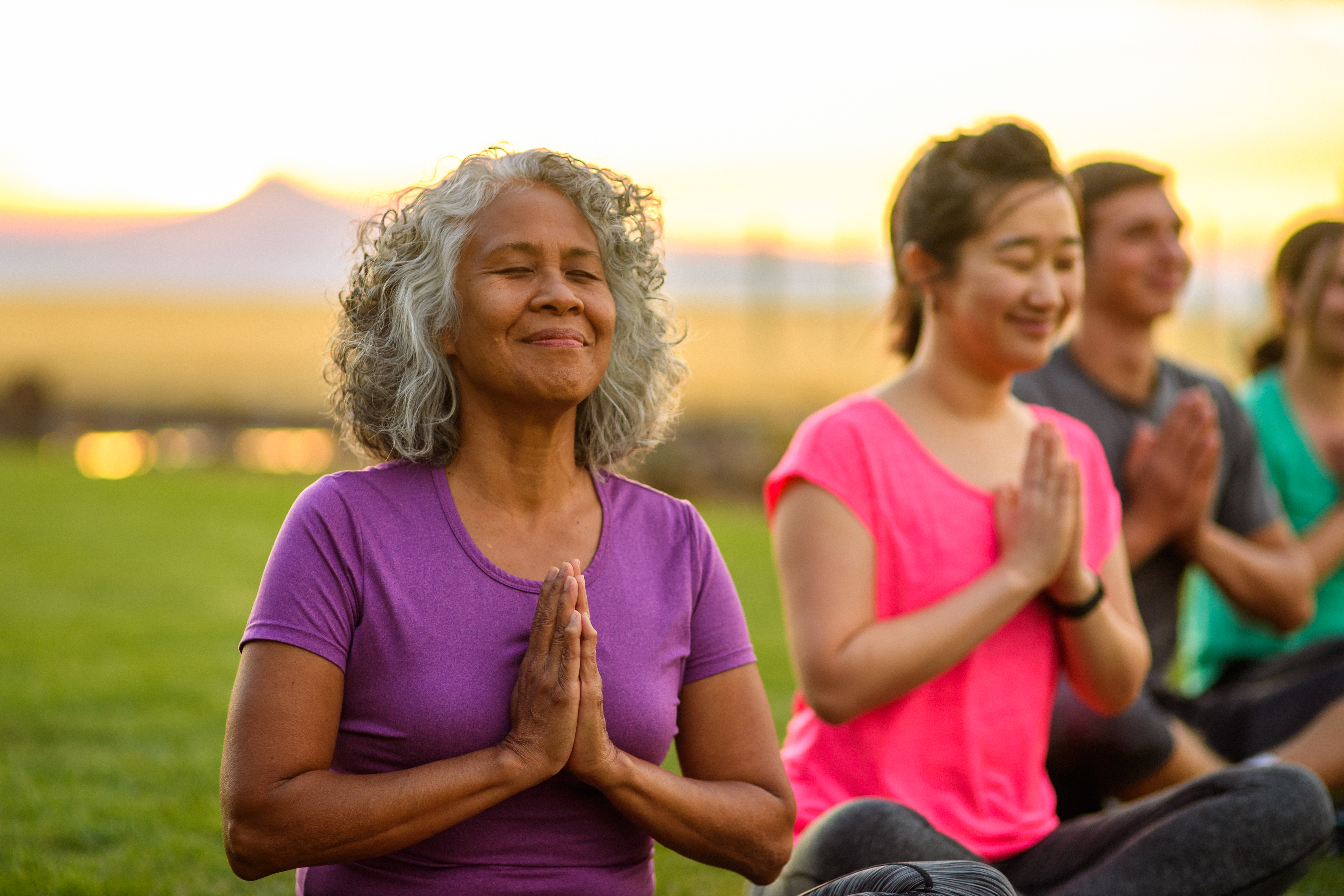 Senior woman meditating in group fitness class