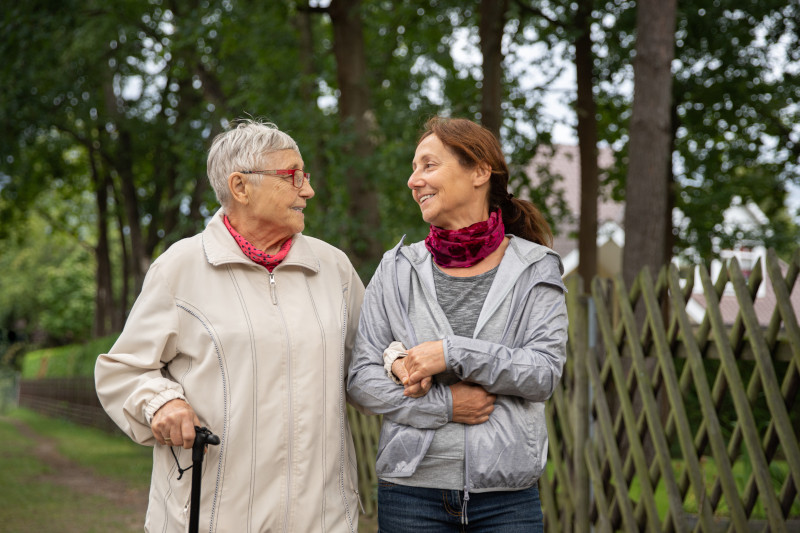 Happy senior woman and caregiver walking outdoors