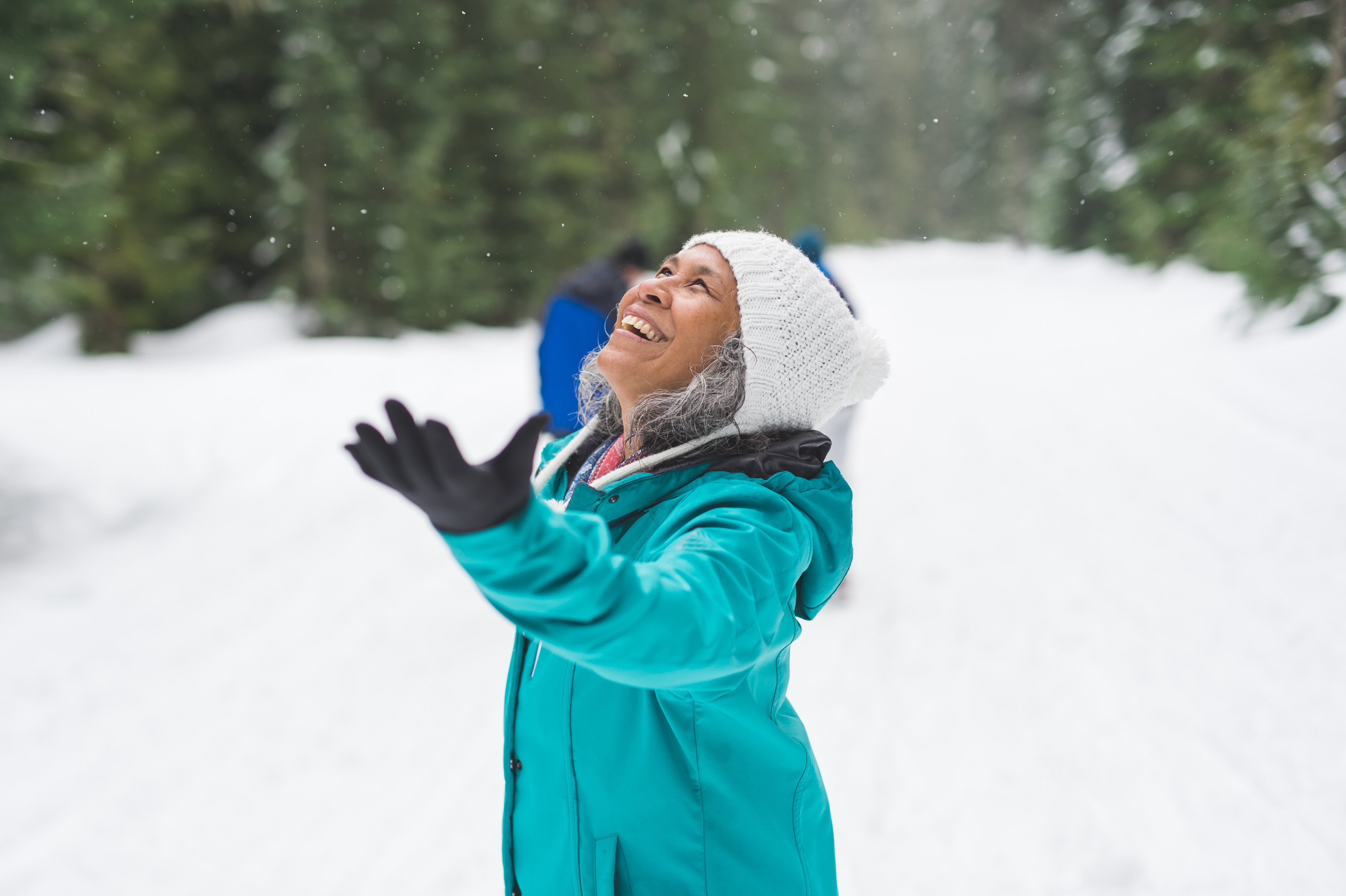 Senior woman holding up her hands in wonderment at the winter wonderland around her