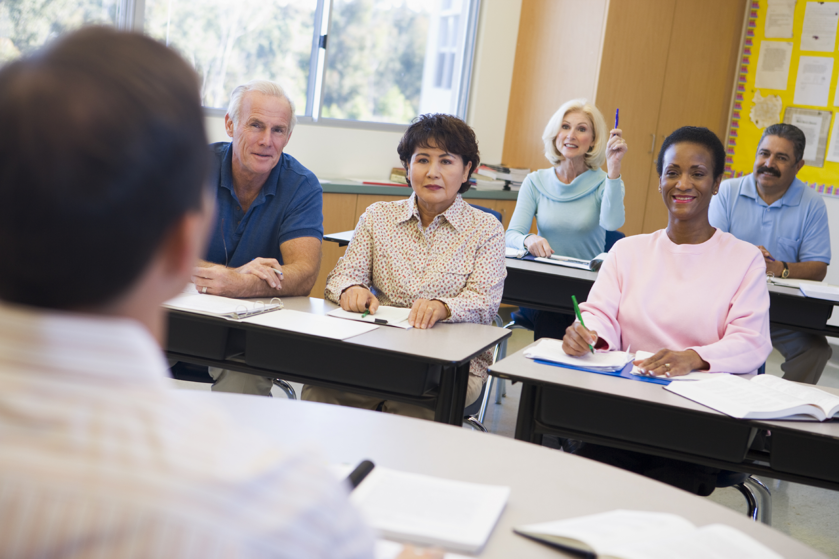 Mature female student raising hand in class