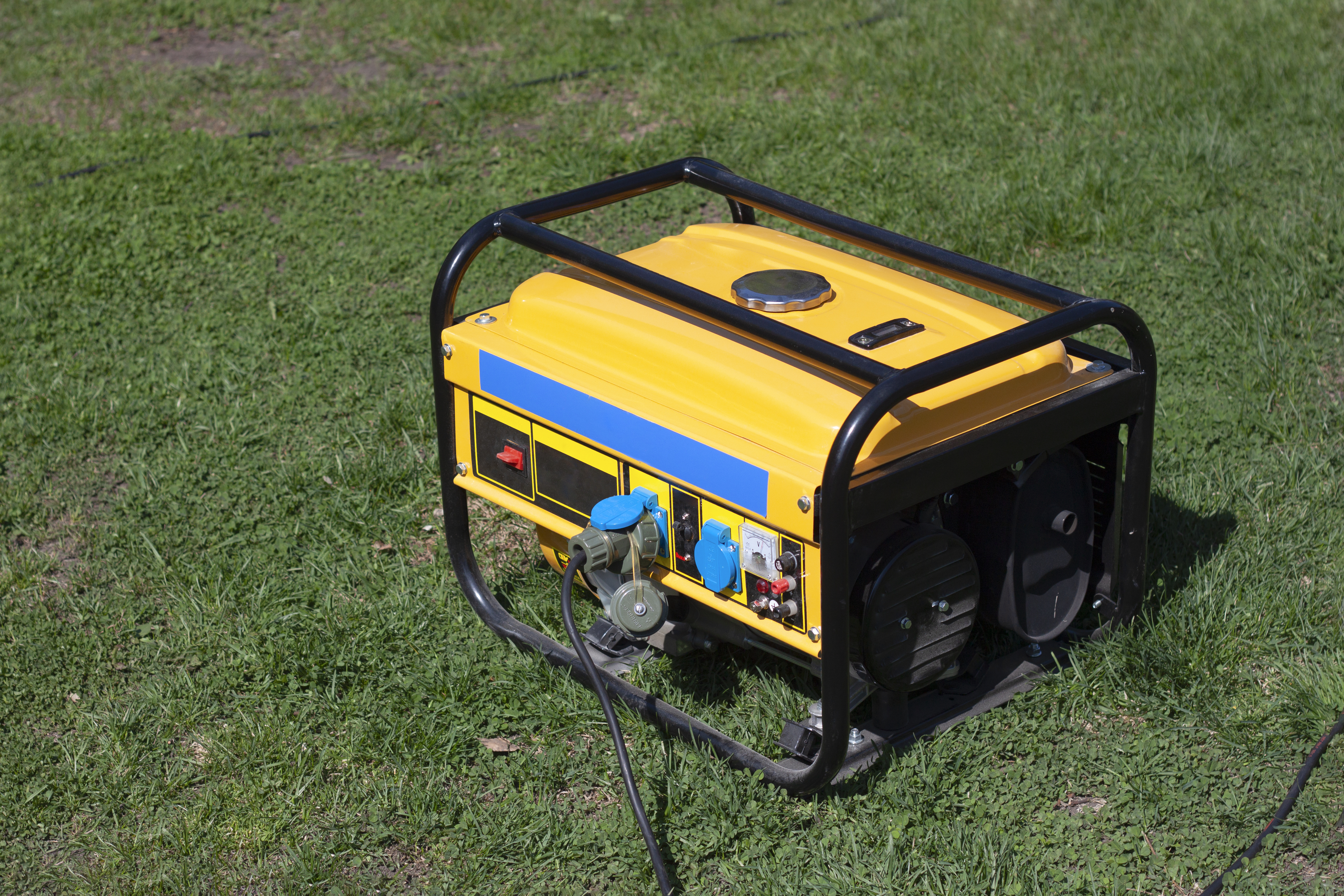 Powerful portable gas or diesel generator to provide electricity. Standing on the grass