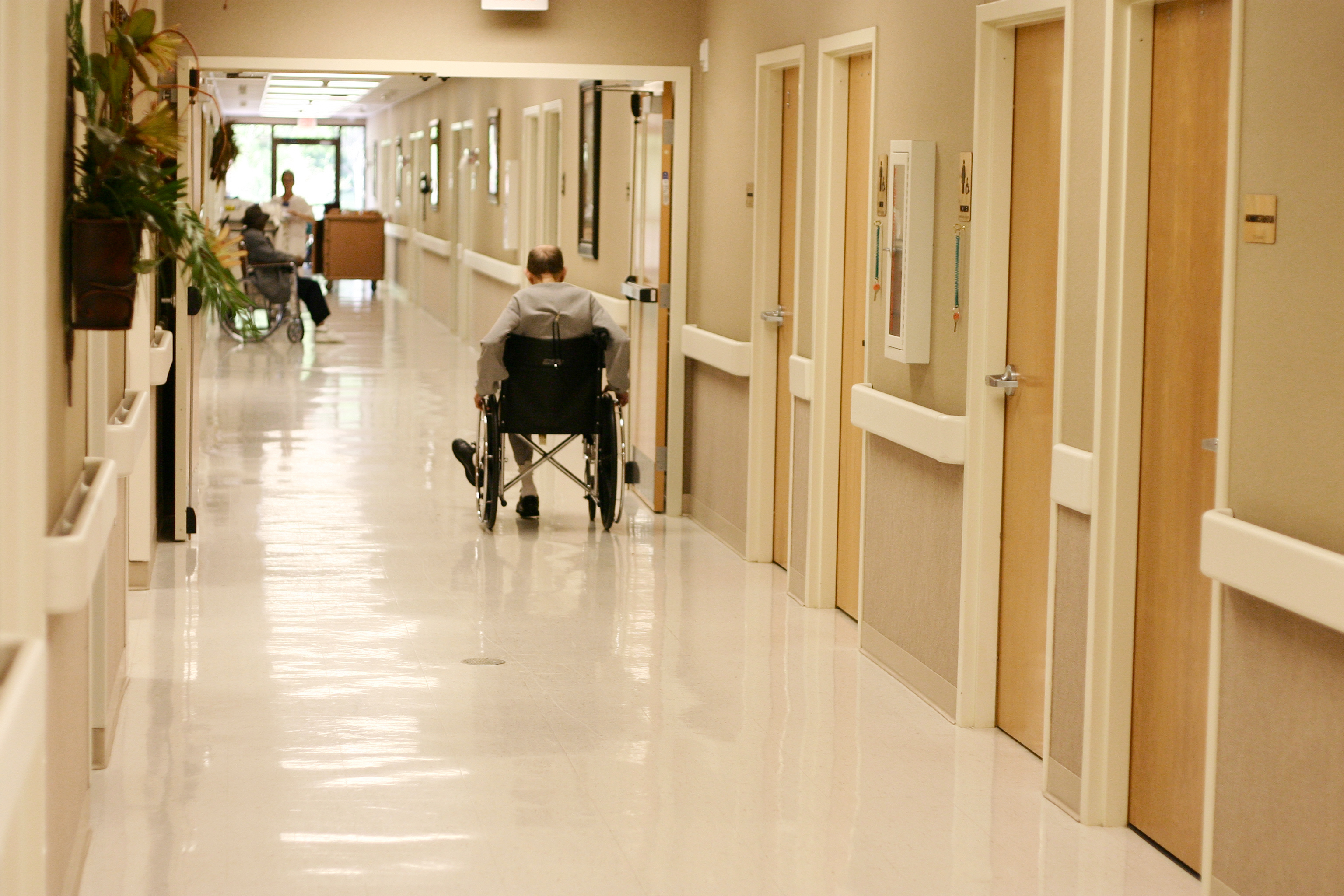 A man in a wheelchair in a nursing home hallway