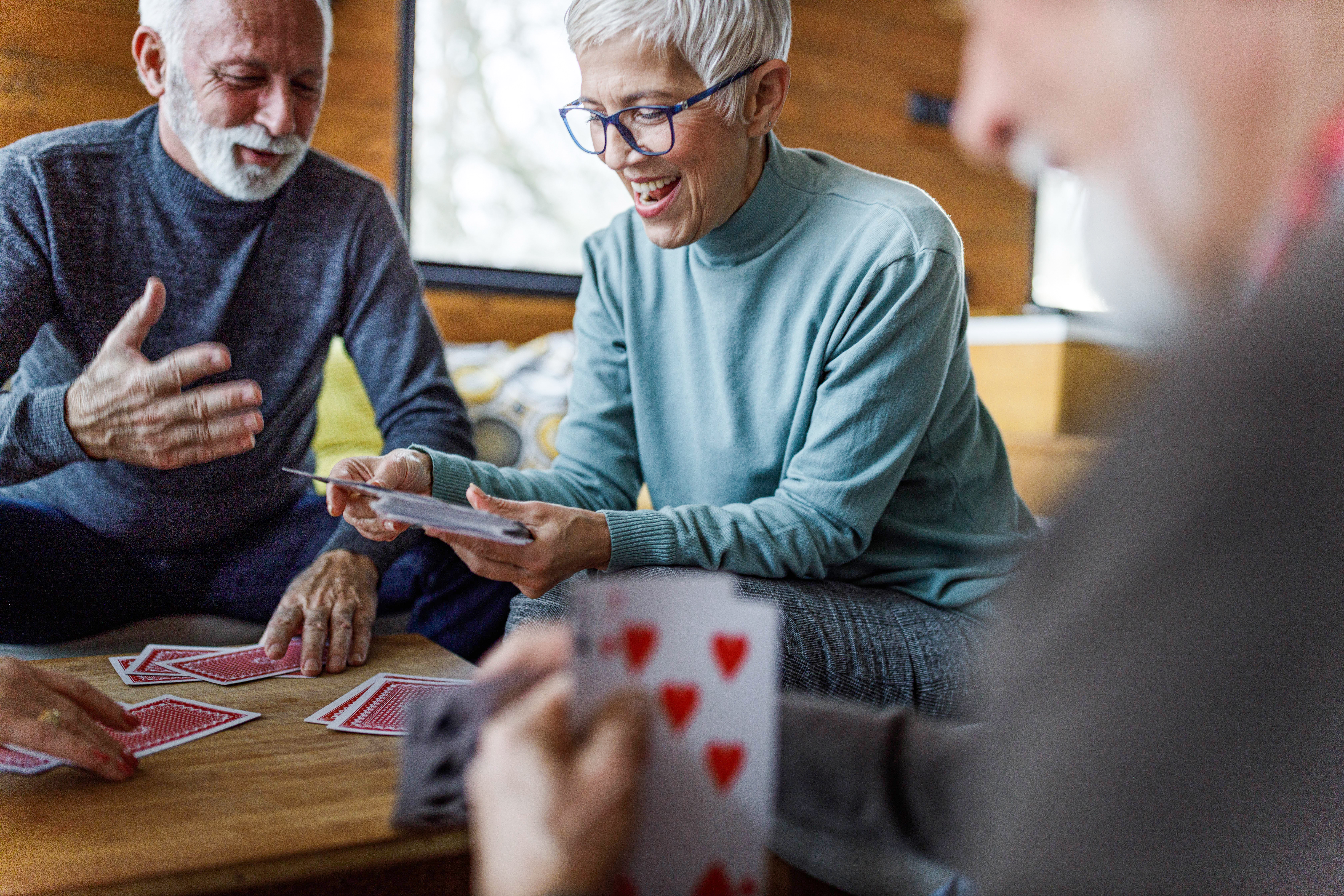 Group of happy seniors playing cards at home.