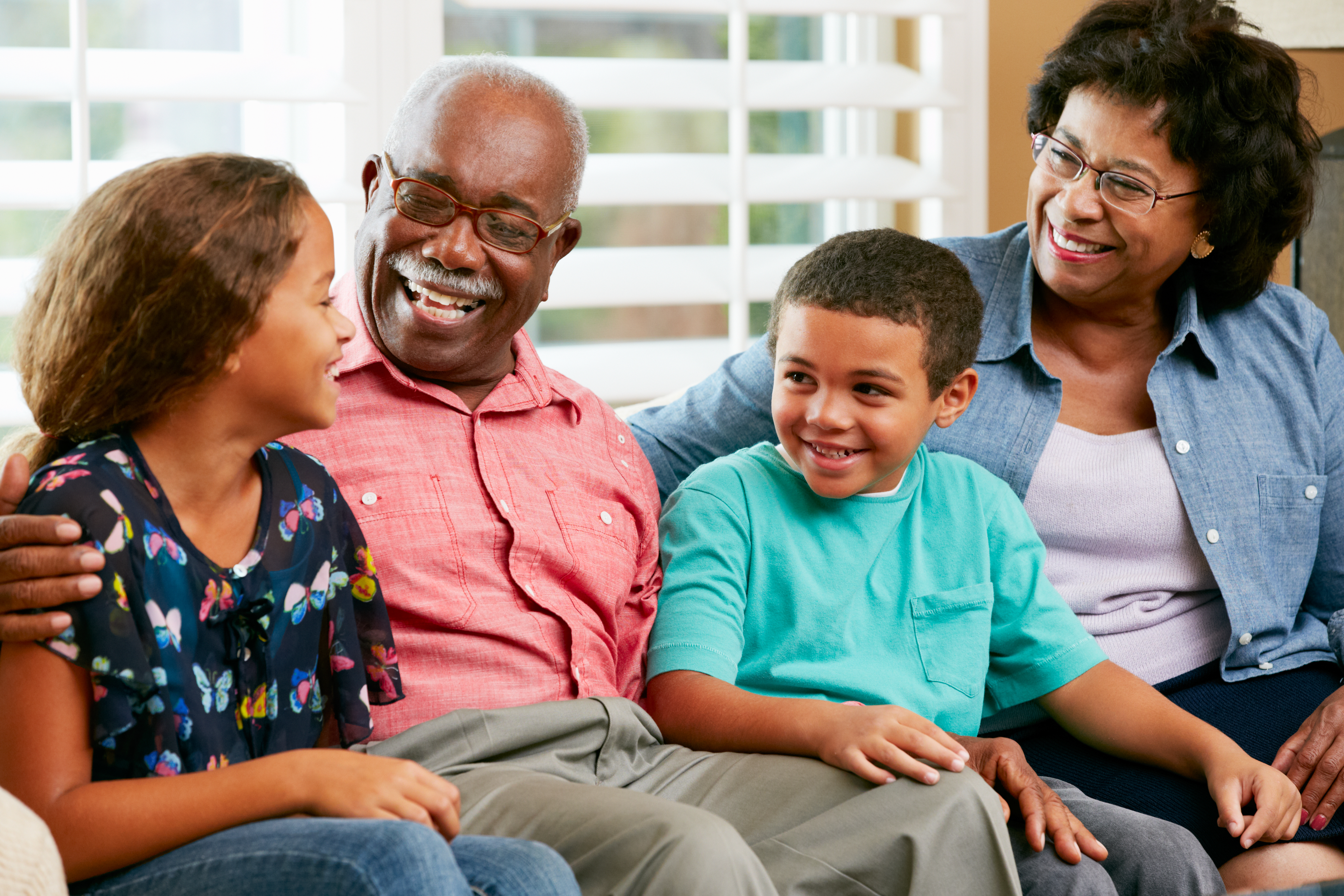 Grandparents With Grandchildren Sitting On Sofa And Talking