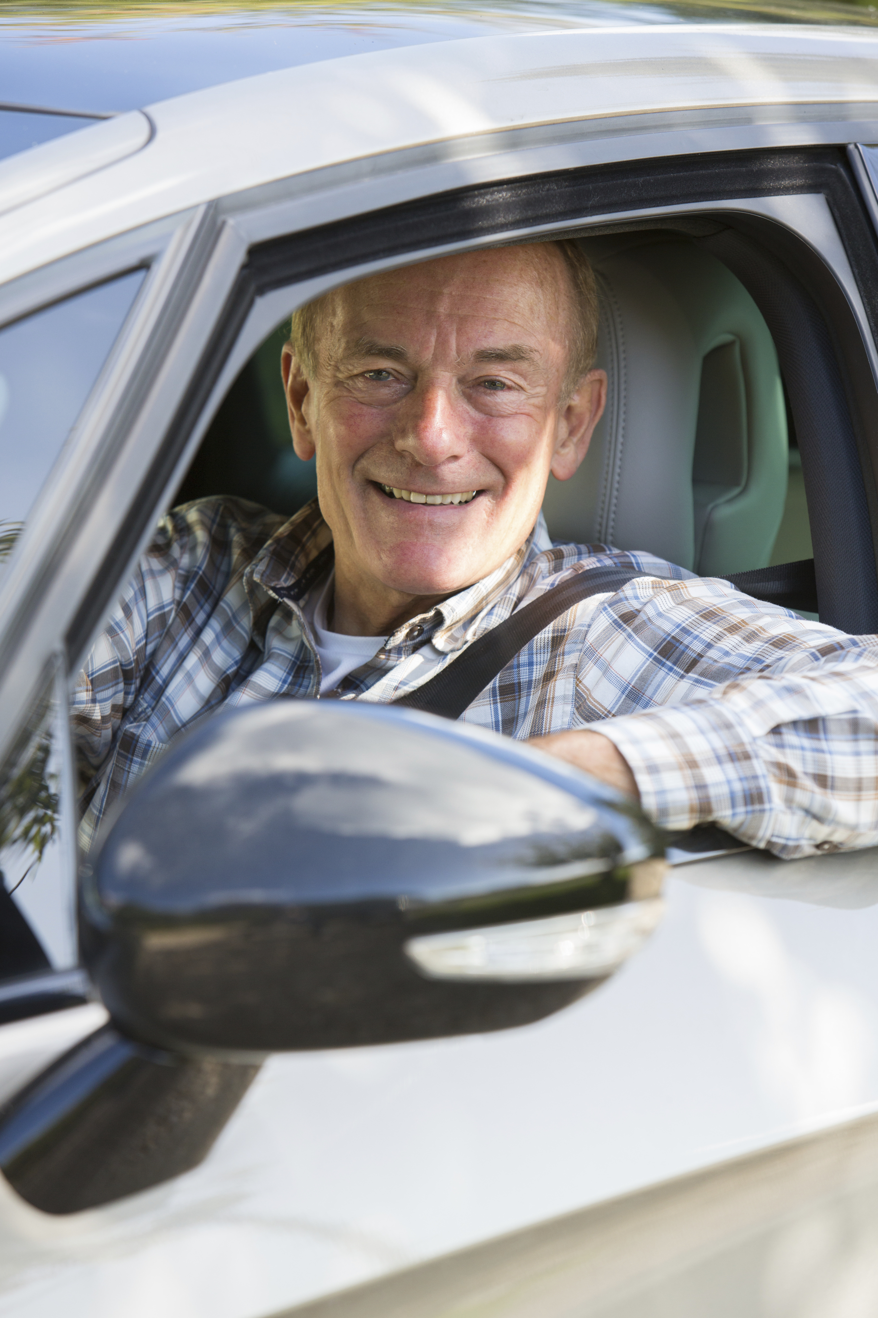 Portrait Of Smiling Senior Man Driving Car