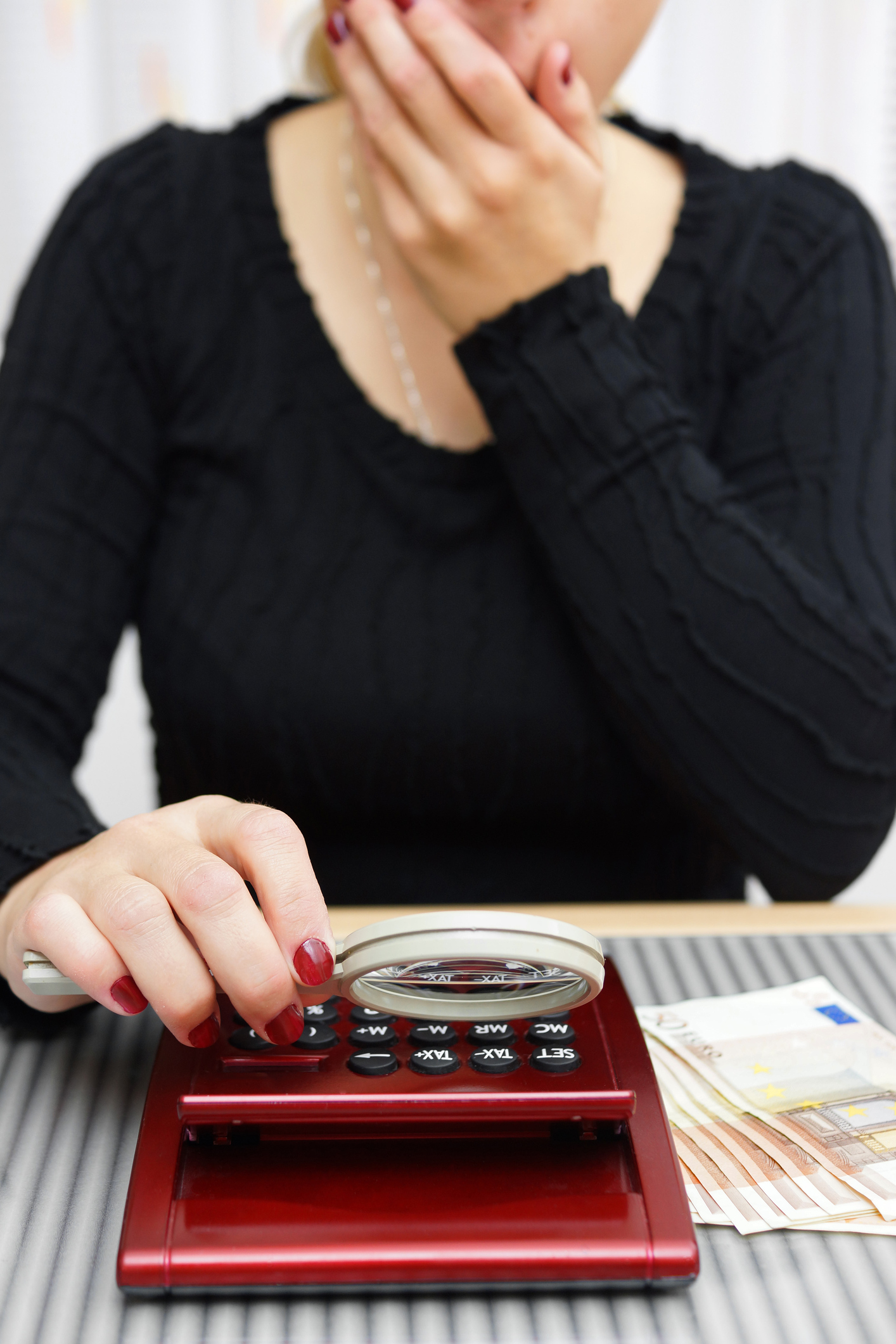 woman watching sum on calculator with magnifying glass