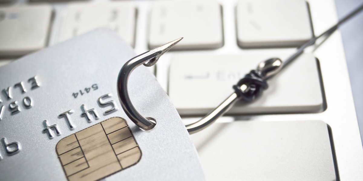 credit card hooked by fishing hook being pulled across a computer keyboard. 