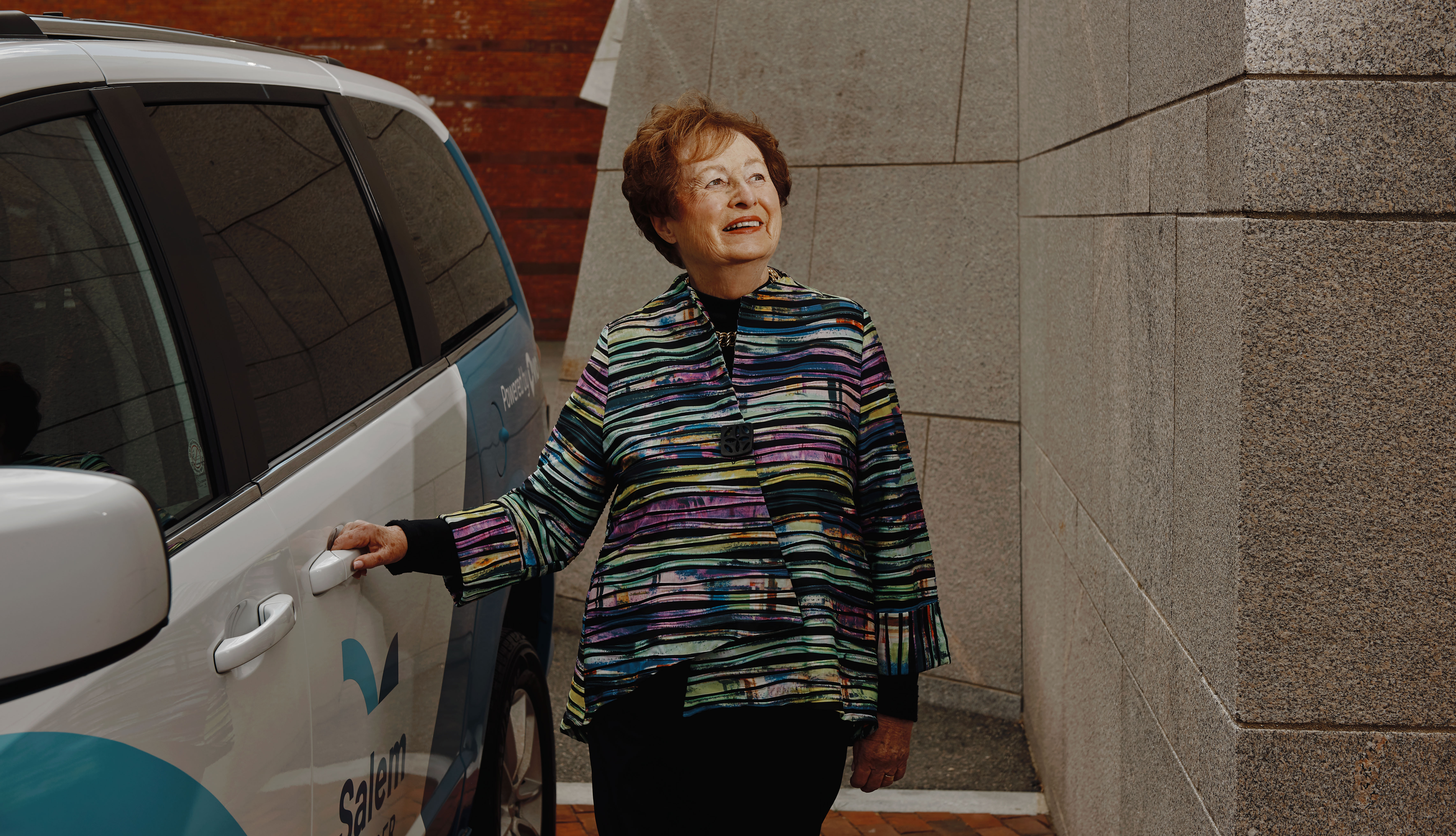 An older woman standing by a van