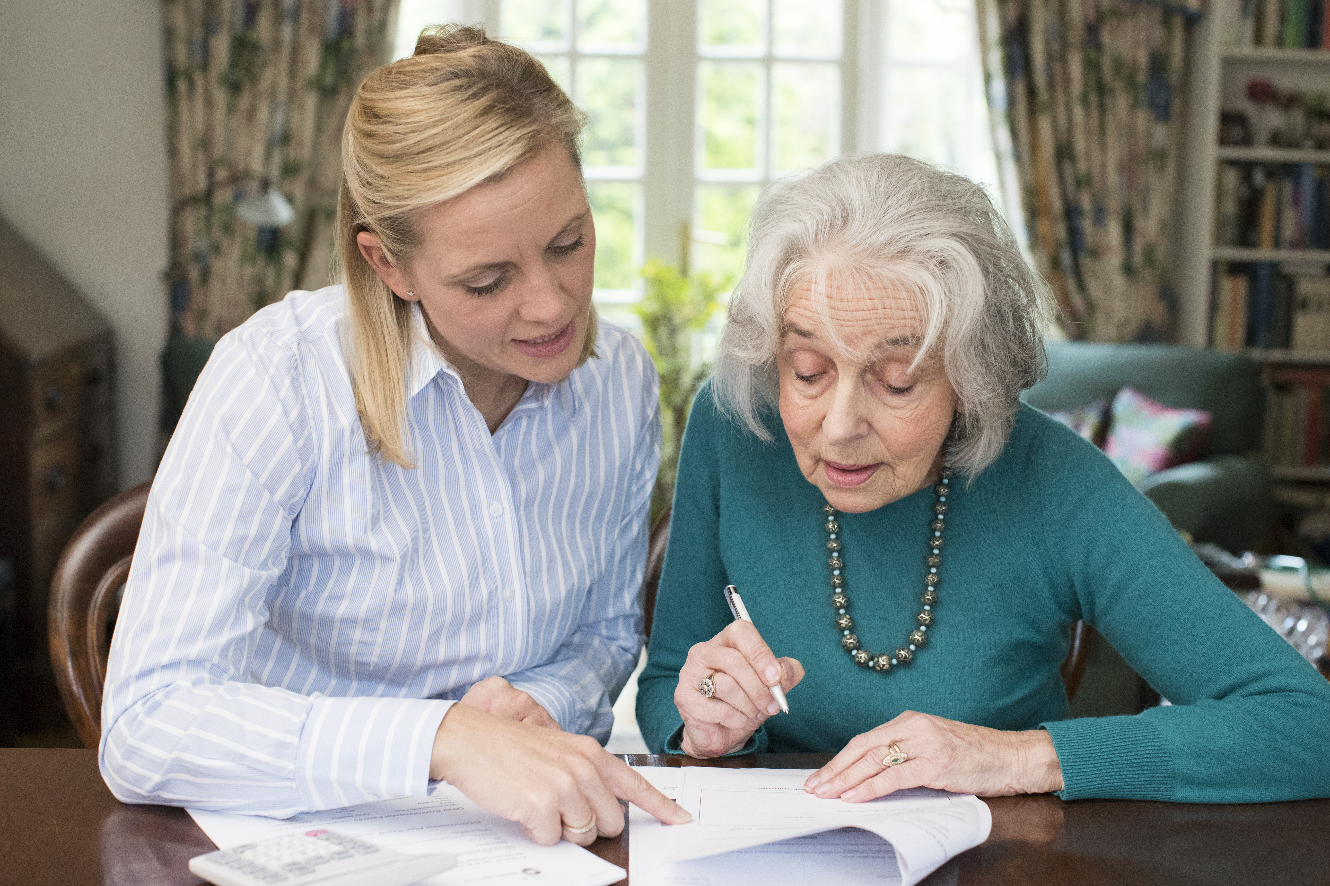 Woman Helping Senior Neighbor With Paperwork