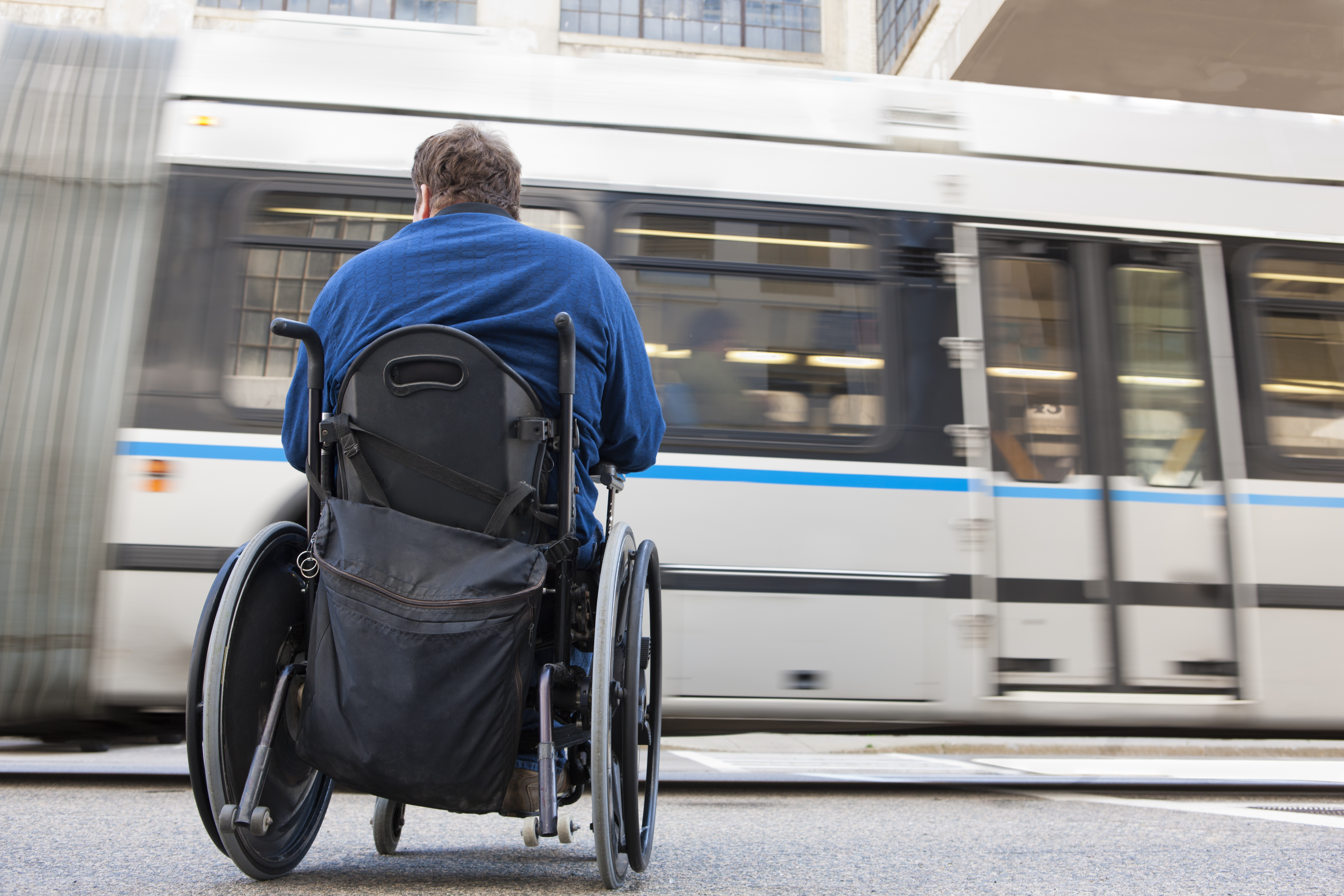 Man in wheelchair with spinal cord injury trying to catch a local bus