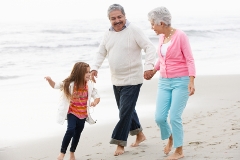 Grandparents Walking Along Beach With Granddaughter