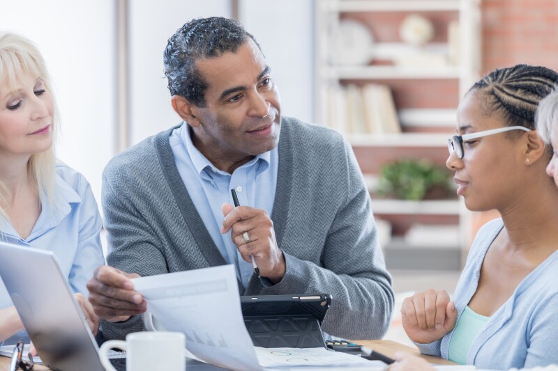 Senior African American businessman reviews document with colleagues
