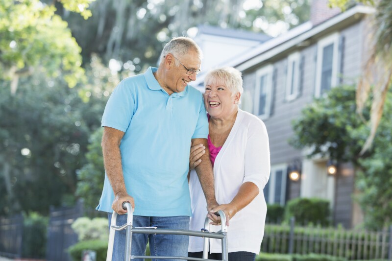 Senior couple walking in neighborhood, man with walker