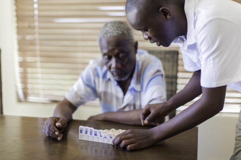 African grandson giving his grandfather medication.