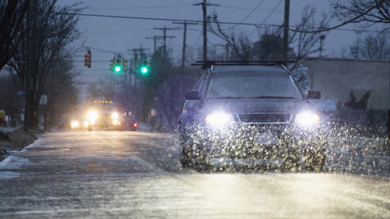 Car driving on snowy urban street at night