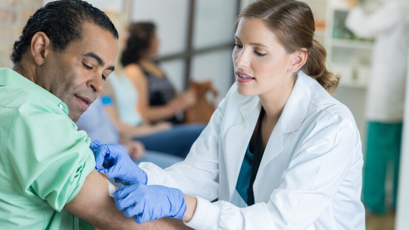 Caring healthcare professional places bandage on man's arm