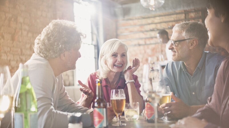 Couples talking and drinking beer at restaurant table