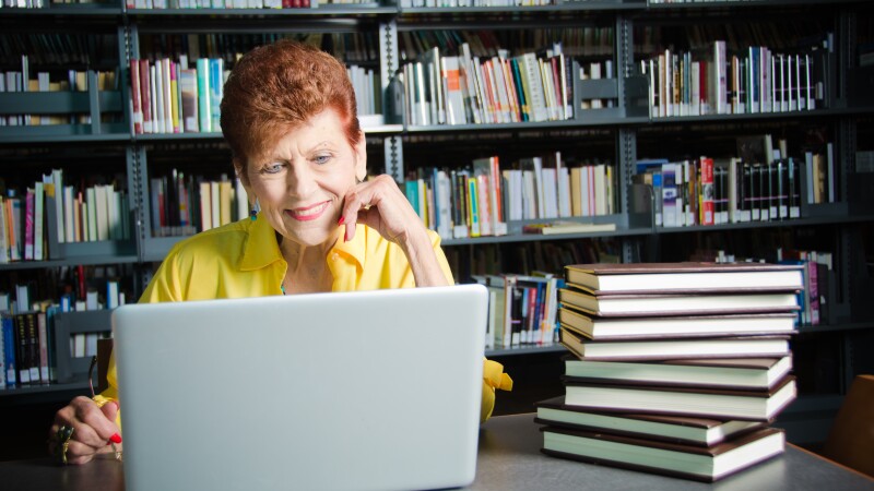 Happy Senior woman with laptop in library
