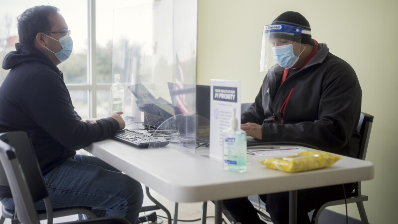 two men with face masks sit at a table