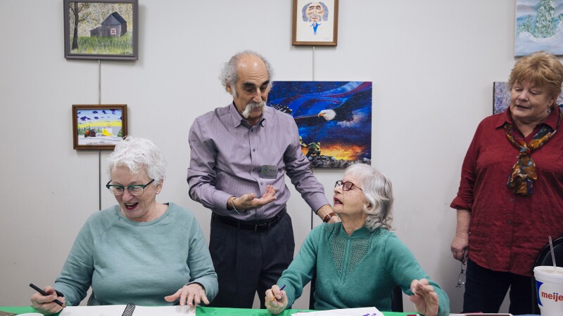 A man speaks with three women at an art class