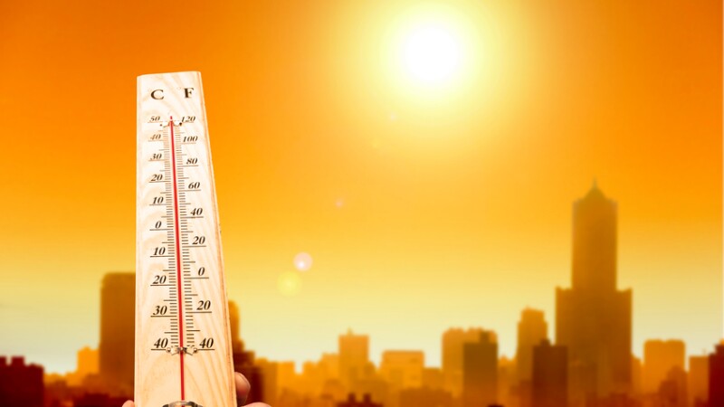 heat wave in the city and hand showing thermometer