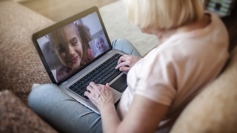 Cute girl talking with her grandmother within video chat on laptop, life in quarantine time