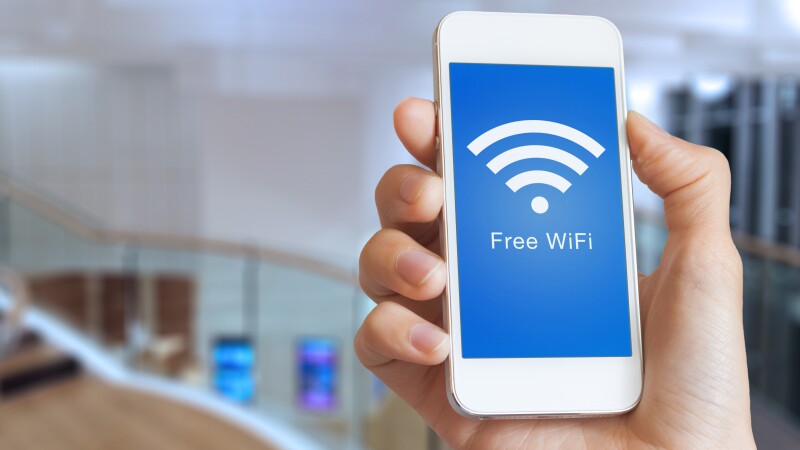 Closeup hand holding smartphone with free WiFi hotspot on screen