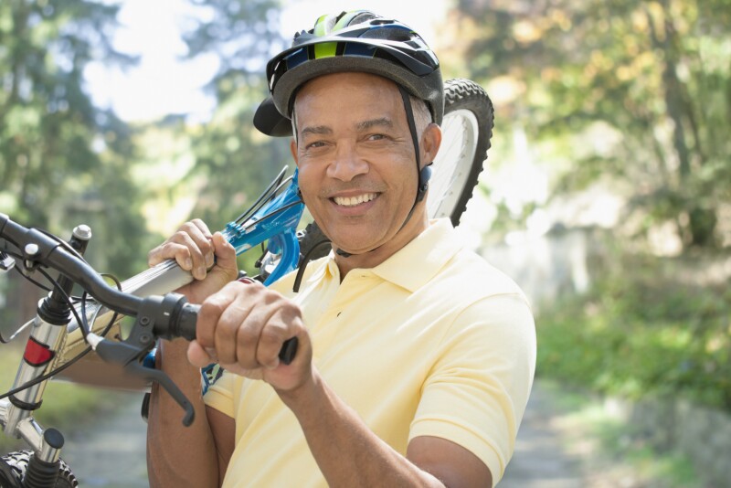 African American man carrying bicycle outdoors