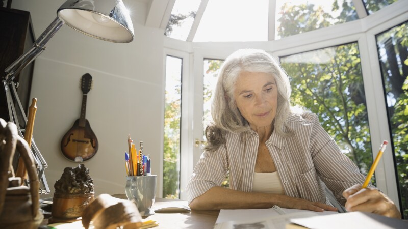 Senior woman writing in home office