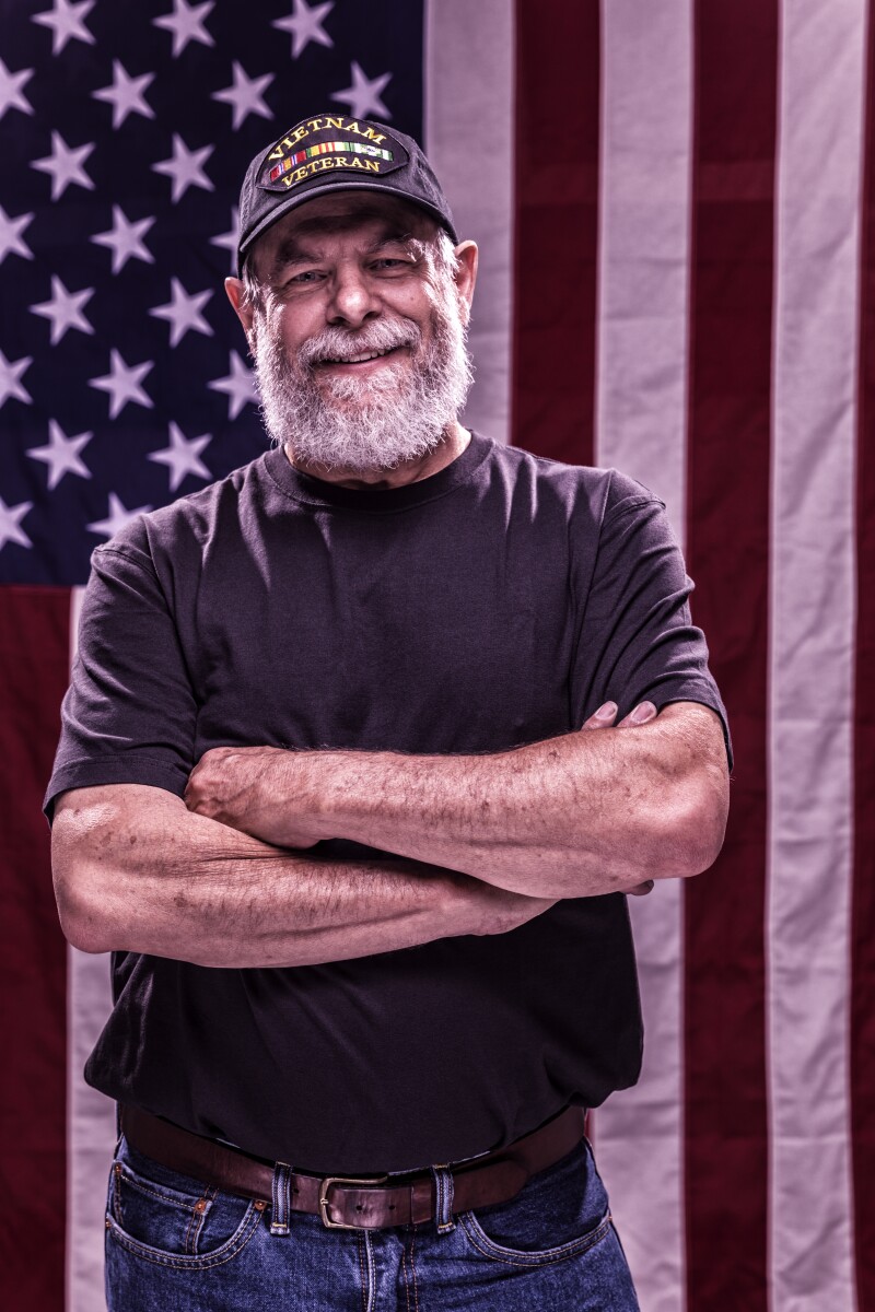 USA Vietnam Veteran With Arms Crossed and American Flag Background