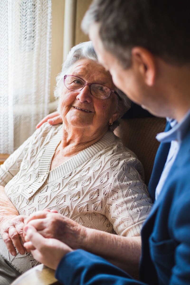 Very old woman looks with a lot of love from a guest who came to visit her at the family home.