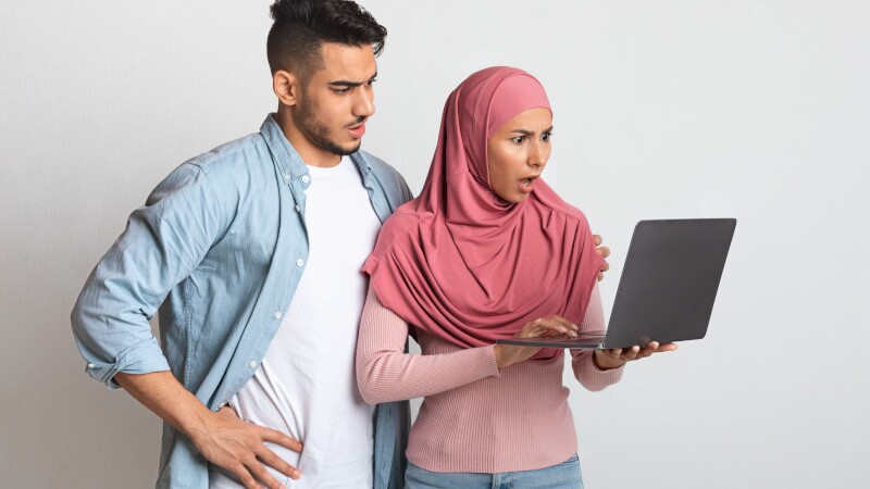 Internet Scams. Confused Young Muslim Couple Looking At Laptop Screen With Worry