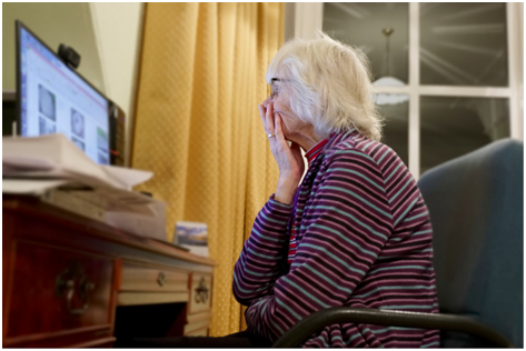 Older woman sitting looking at computer screen.