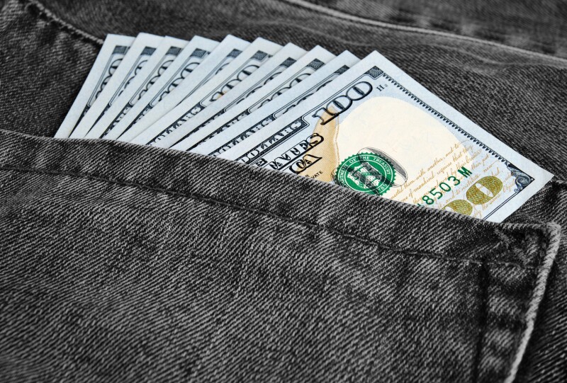 Many greenback in a pocket of jeans