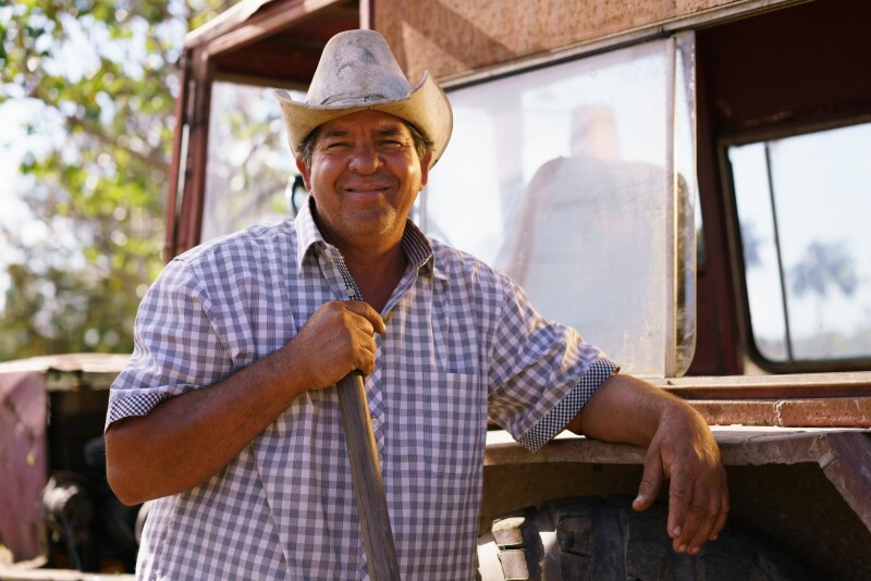 Portrait Happy Man Farmer Leaning On Tractor Looking At Camera