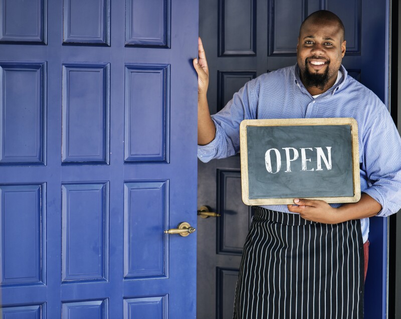 A cheerful small business owner with open sign