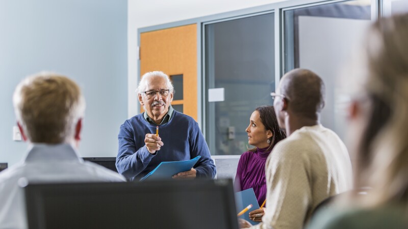 Senior Hispanic man teaching adult students
