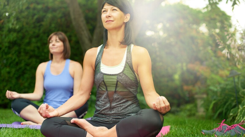 Two mature women keeping fit by doing yoga in the