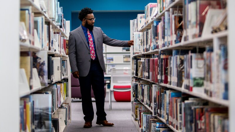 A man examines library bookshelves