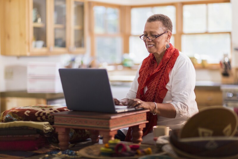 Older mixed race woman using laptop in home office