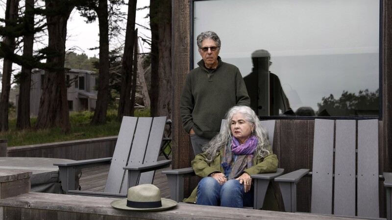 An older couple sit outside on their deck