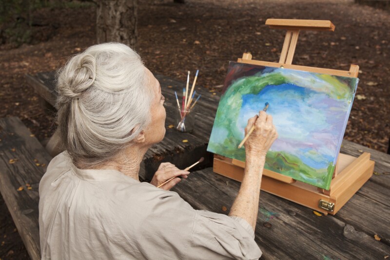 Older Caucasian woman painting in park