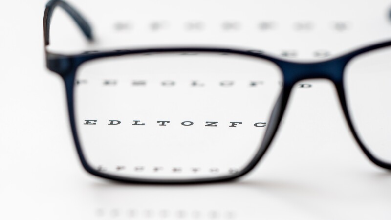 Reading black eyeglasses and eye chart close-up, shallow depth of field