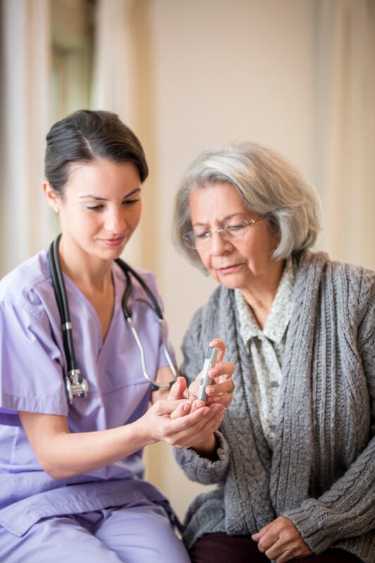 Nurse giving blood sugar test to patient in home