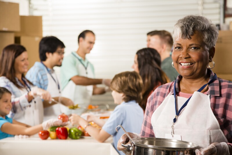 Group of volunteers serve food at community soup kitchen. Charity.