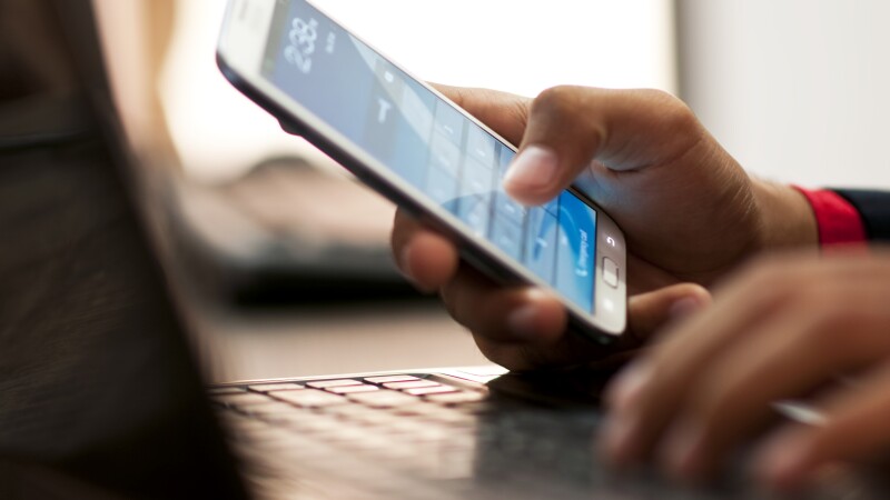 Businessman hand using laptop and mobile phone in office