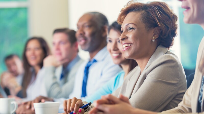 African American businesswoman listening to seminar speaker at business conference