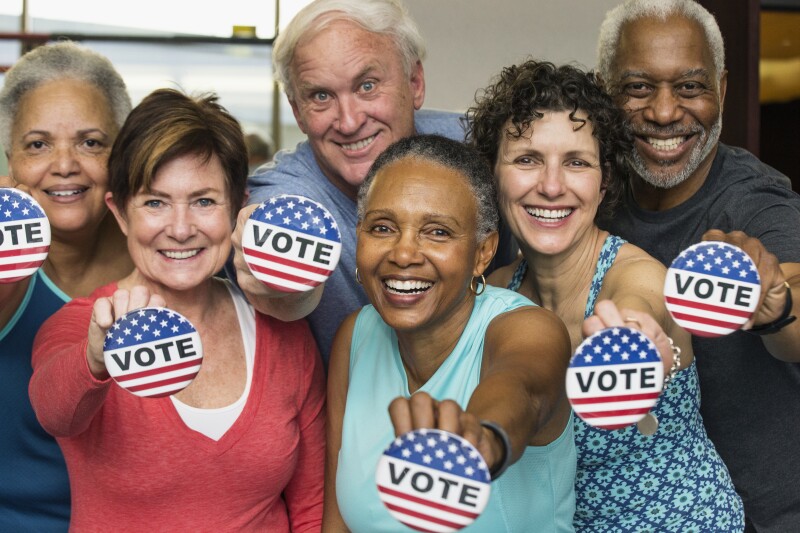 Senior friends holding Vote' buttons