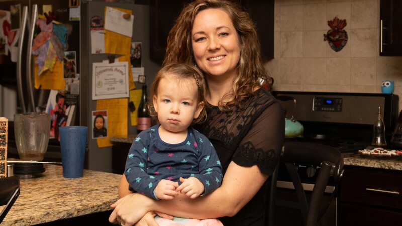 Mom sitting with her toddler daughter on her lap in the kitchen