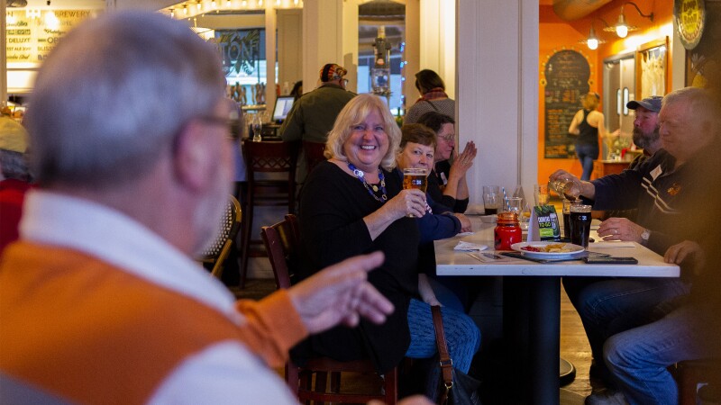 A group of adults enjoy beer and food at a brewery taproom